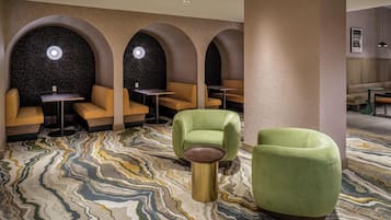 A modern lounge area with seating arrangements, including sofas and chairs, and a patterned carpet.