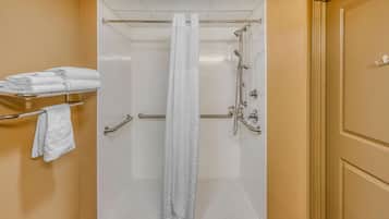 A shower with a glass door, a towel rack with folded towels, and a shower control panel.