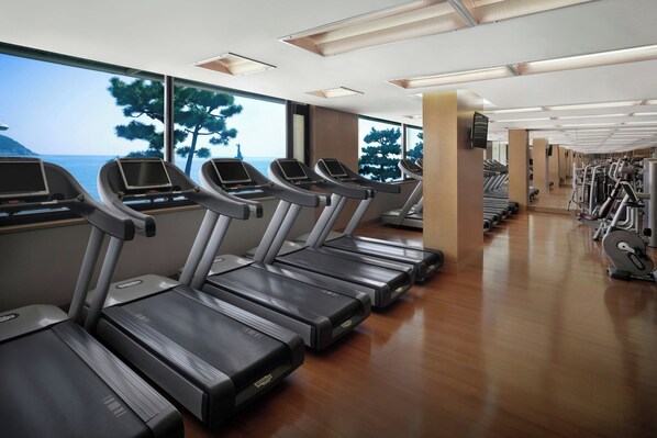 A gym with treadmills aligned along the wall, large windows, and exercise equipment. - The Westin Josun Busan (Busan)