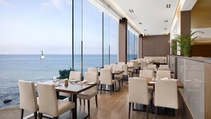 A restaurant with a view of the sea, featuring large windows, wooden flooring, and modern furniture. - The Westin Josun Busan (Busan)