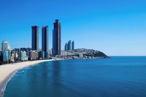 A coastal cityscape with high-rise buildings, a beach, and a hilly area in the background. - The Westin Josun Busan (Busan)