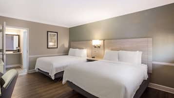 Une chambre d’hôtel avec deux lits, un bureau et une chaise.