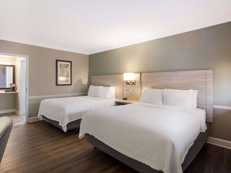 A hotel room with two beds, a desk, and a chair.