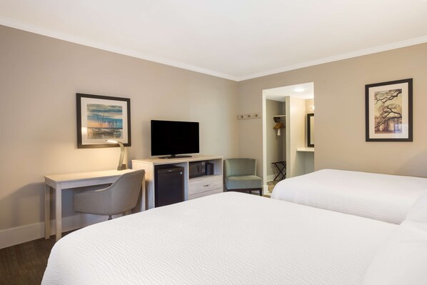 A hotel room with a bed, a desk with a television, a chair, and a wardrobe.