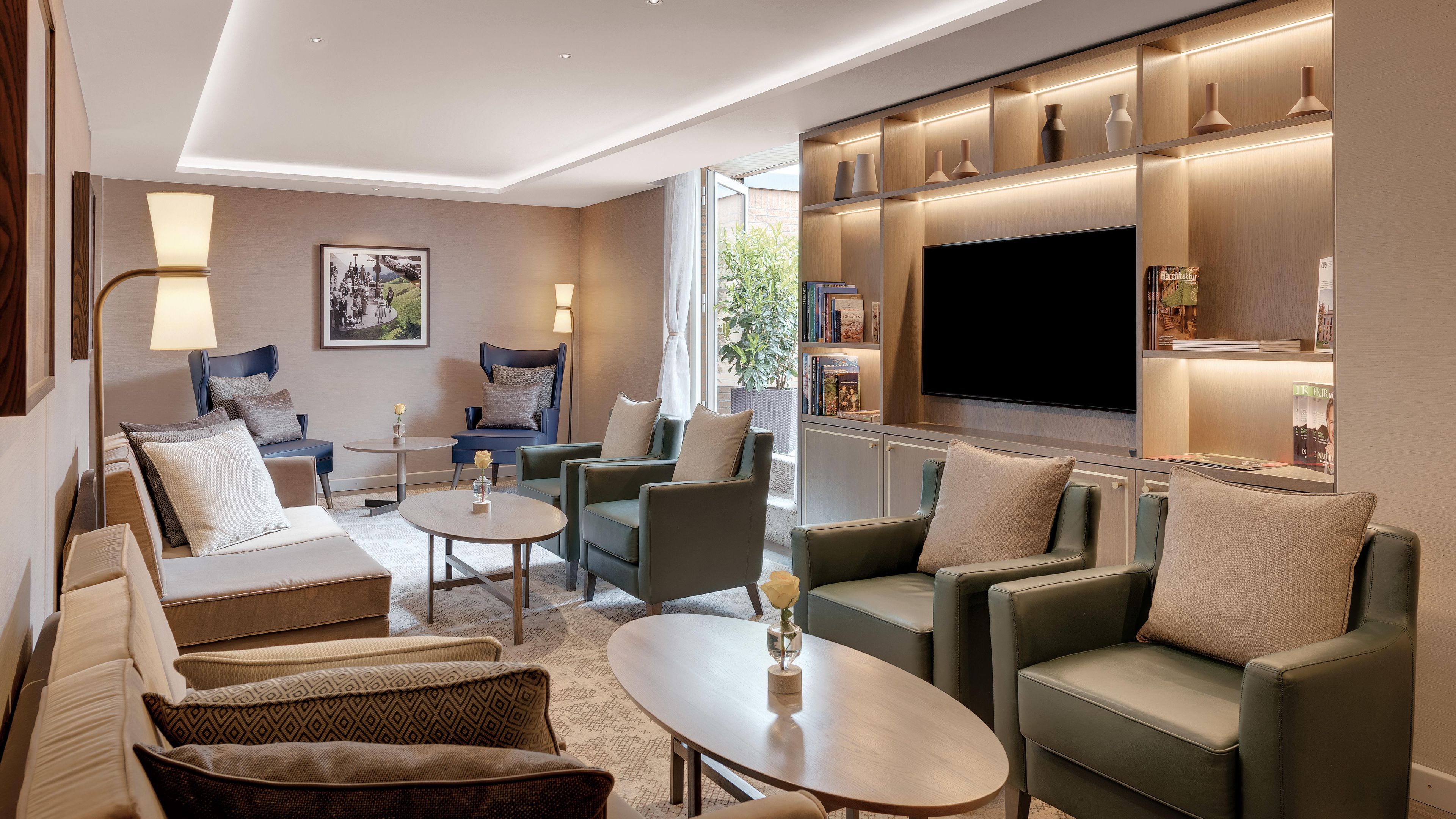 A modern living room with a flat-screen TV, comfortable seating, and a bookshelf.