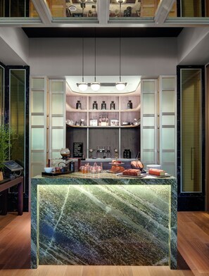 A modern bar area with a marble countertop, shelves with bottles, and a coffee machine. - Hilton Munich City (Munich)