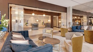 A modern hotel lobby with a reception desk, seating area, and decorative lighting. - Hilton Munich City (Munich)