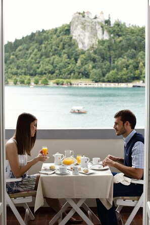 A dining table with breakfast items and a scenic view of a lake and mountains. - Grand Hotel Toplice - Sava Hotels & Resorts (Bled)