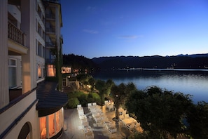 A lakeside hotel patio with outdoor seating and a view of the lake and mountains. - Grand Hotel Toplice - Sava Hotels & Resorts (Bled)