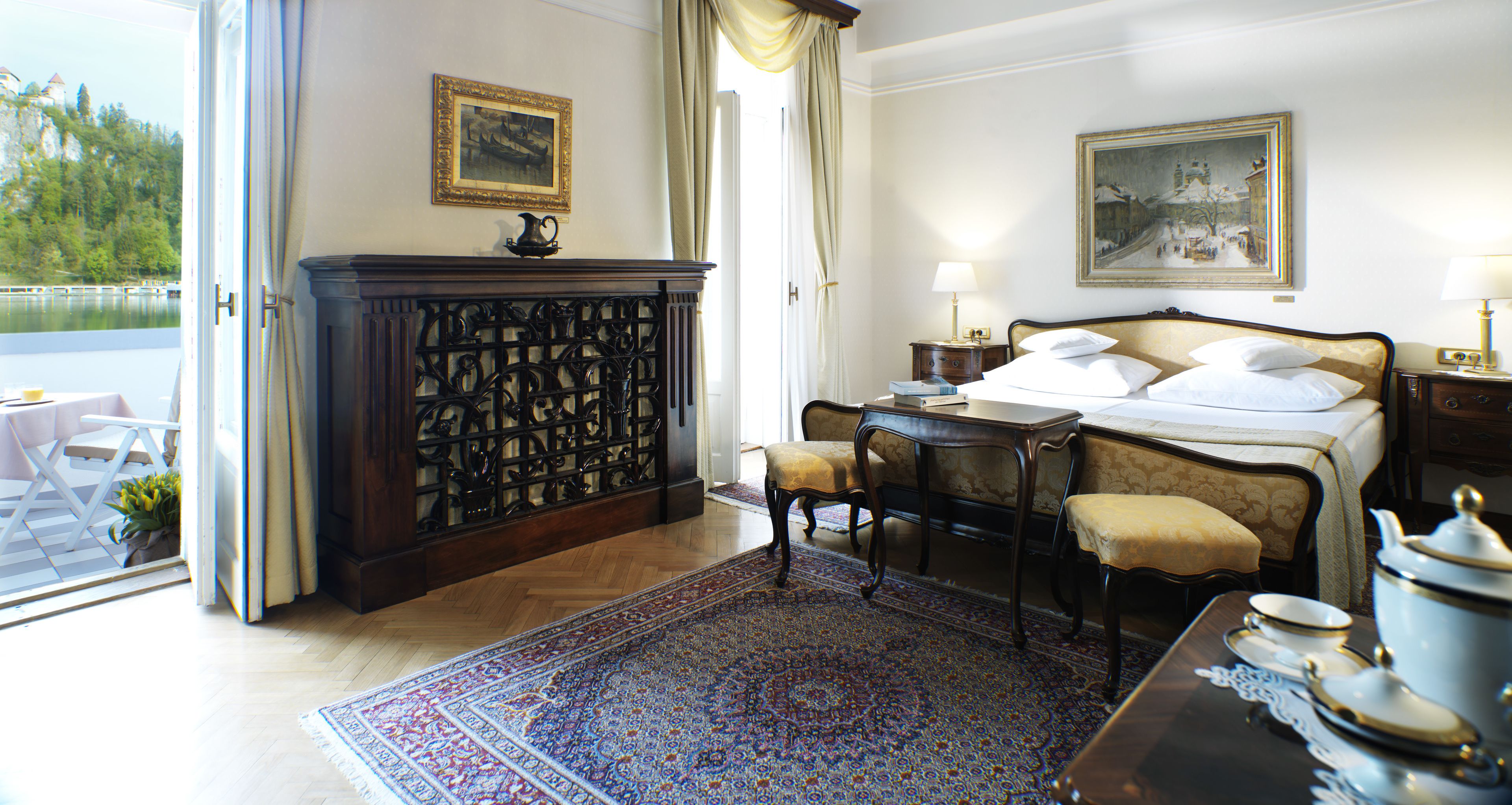 Una habitación de hotel con cama, escritorio, silla, ventana grande y vista a un lago.