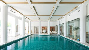 An indoor swimming pool with clear blue water, surrounded by white columns and a high ceiling with gold trim. - Grand Hotel Toplice - Sava Hotels & Resorts (Bled)