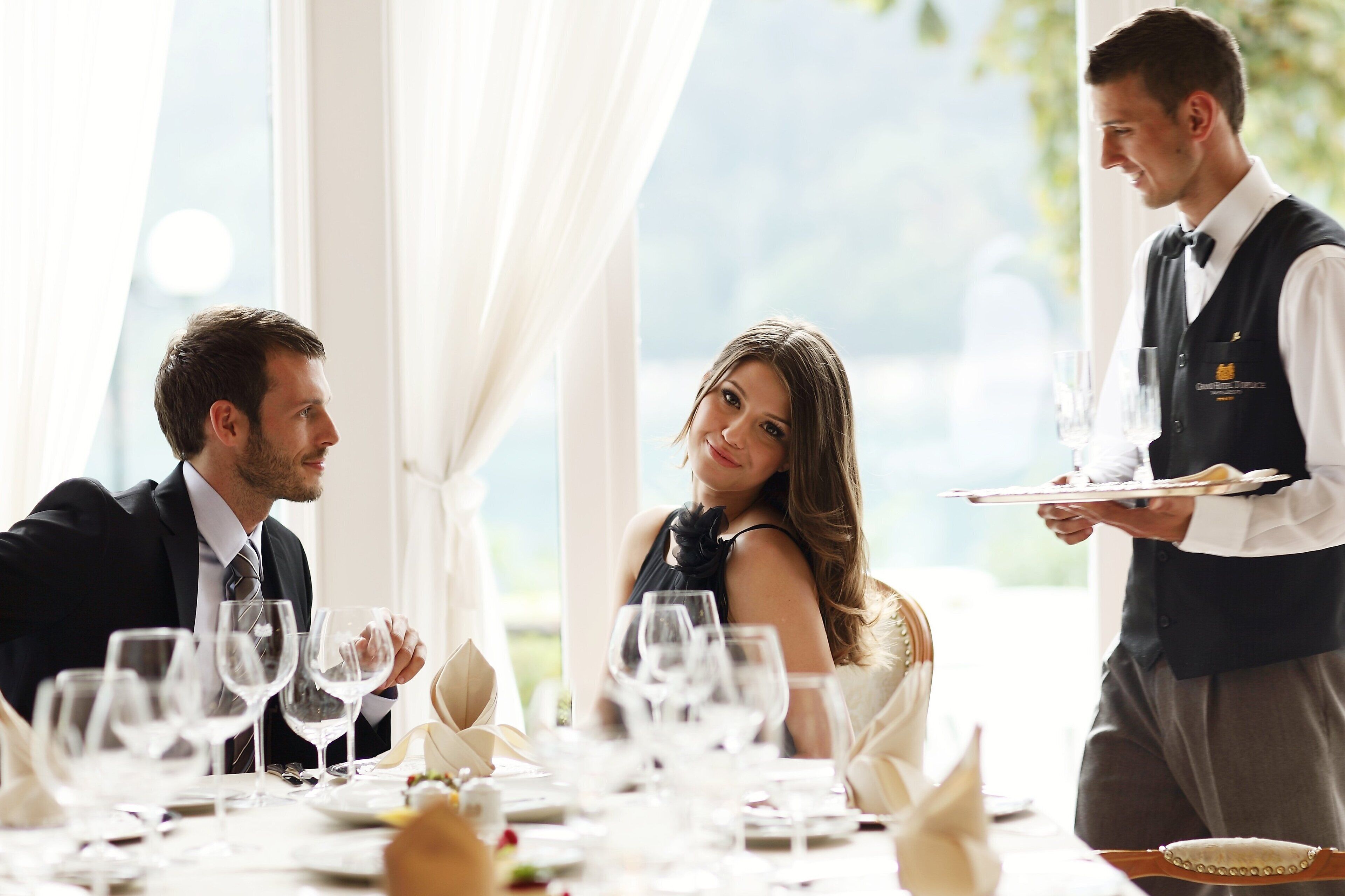 A formal dining setting with a waiter attending to guests.