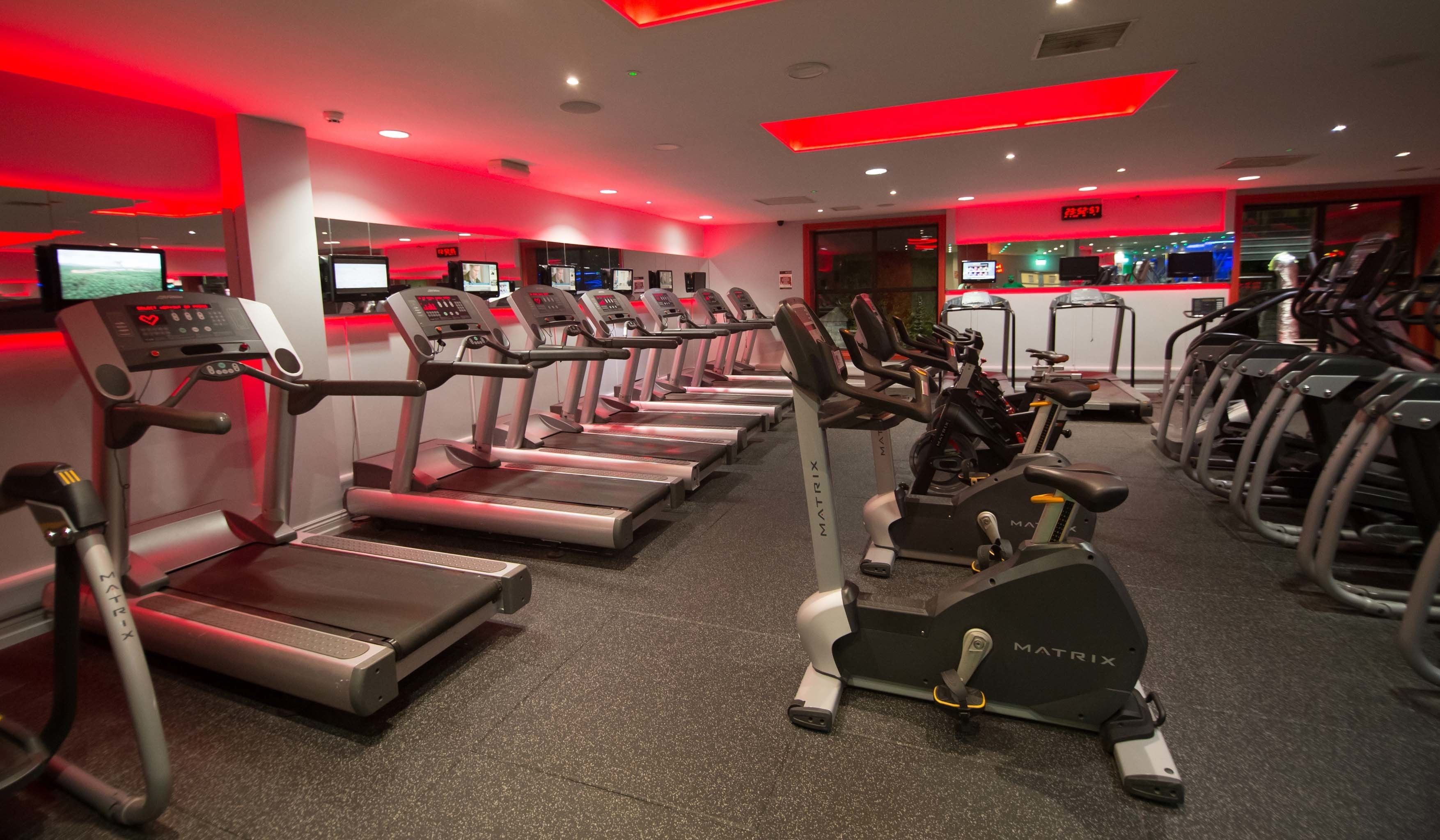 Un gimnasio con cintas de correr, bicicletas estáticas y elípticas.