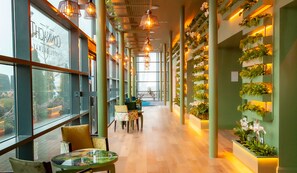 A spacious hotel lobby with high ceilings, modern lighting, and a green wall adorned with plants. - The Connacht Hotel (Galway)
