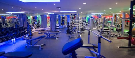 Une salle de sport équipée de divers appareils d’exercice, de miroirs et de supports pour les poids.