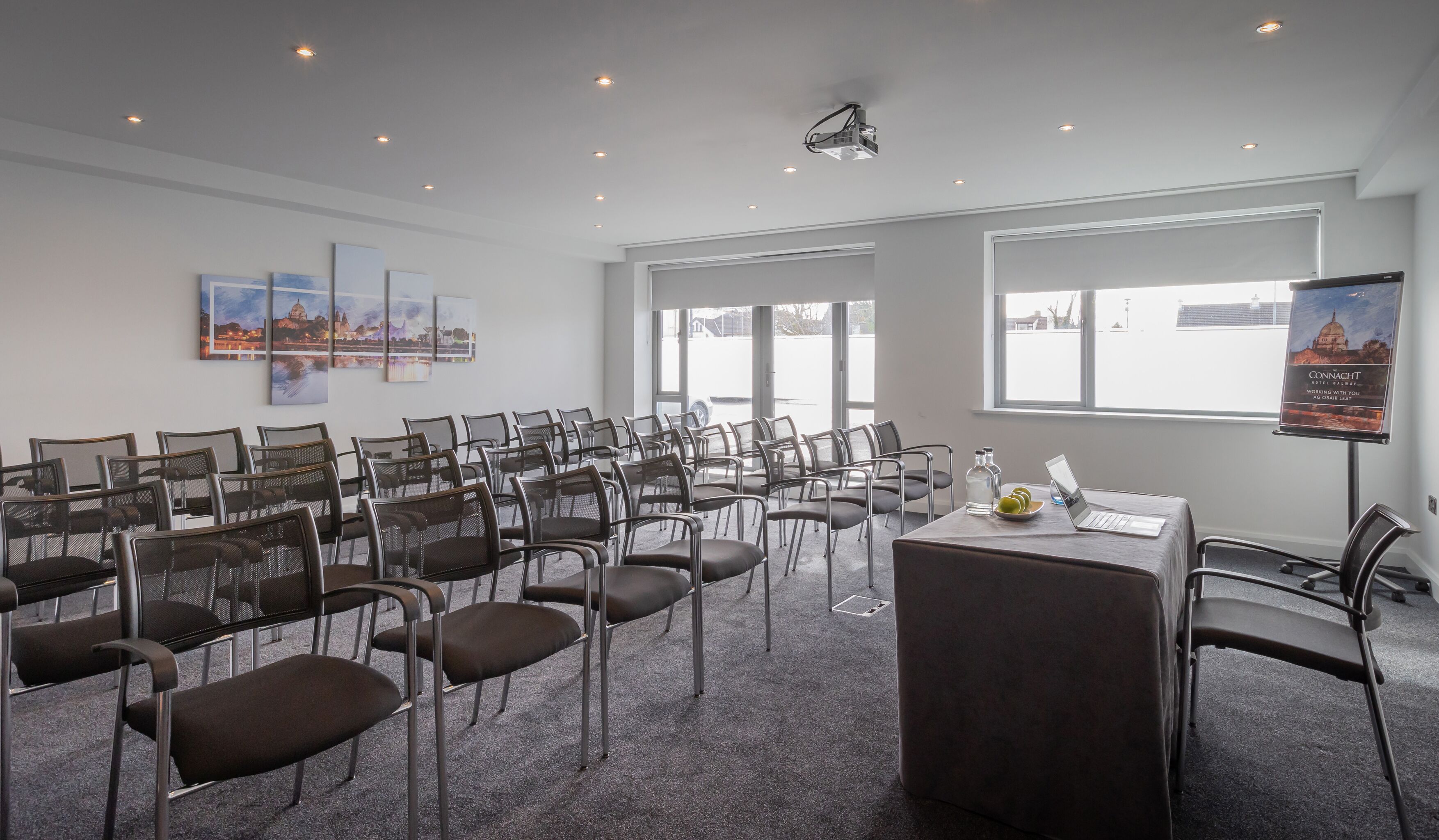 A conference room with rows of chairs, a podium, a laptop, and a poster on the wall.