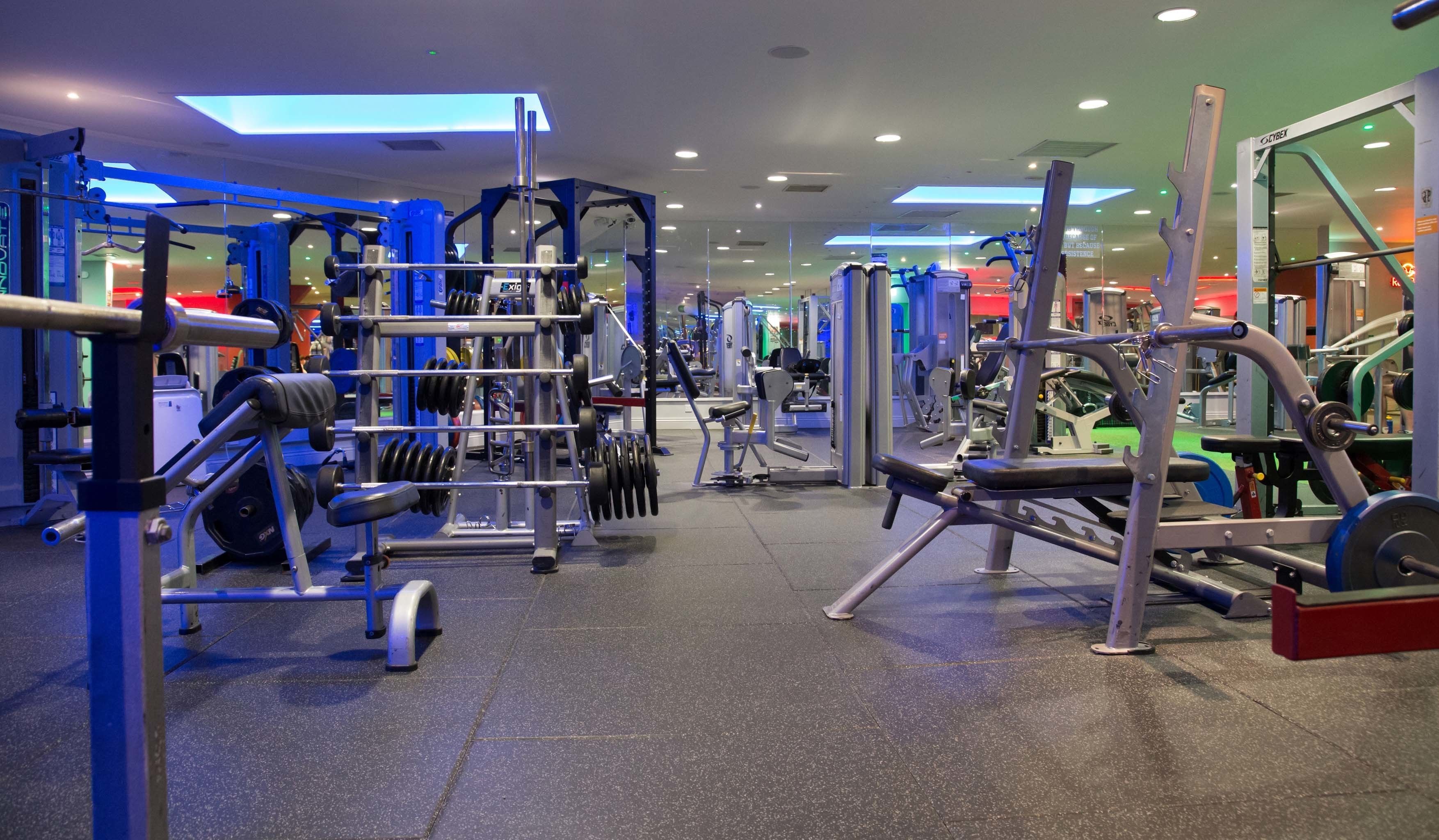 Un gimnasio con diferentes máquinas de ejercicio y pesas.