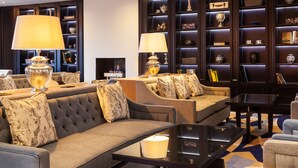 Un área de descanso moderna con sofás, lámparas y una estantería llena de objetos decorativos.