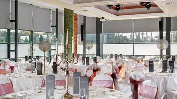 A banquet hall with tables set for a formal event, featuring white tablecloths, silverware, and glassware.