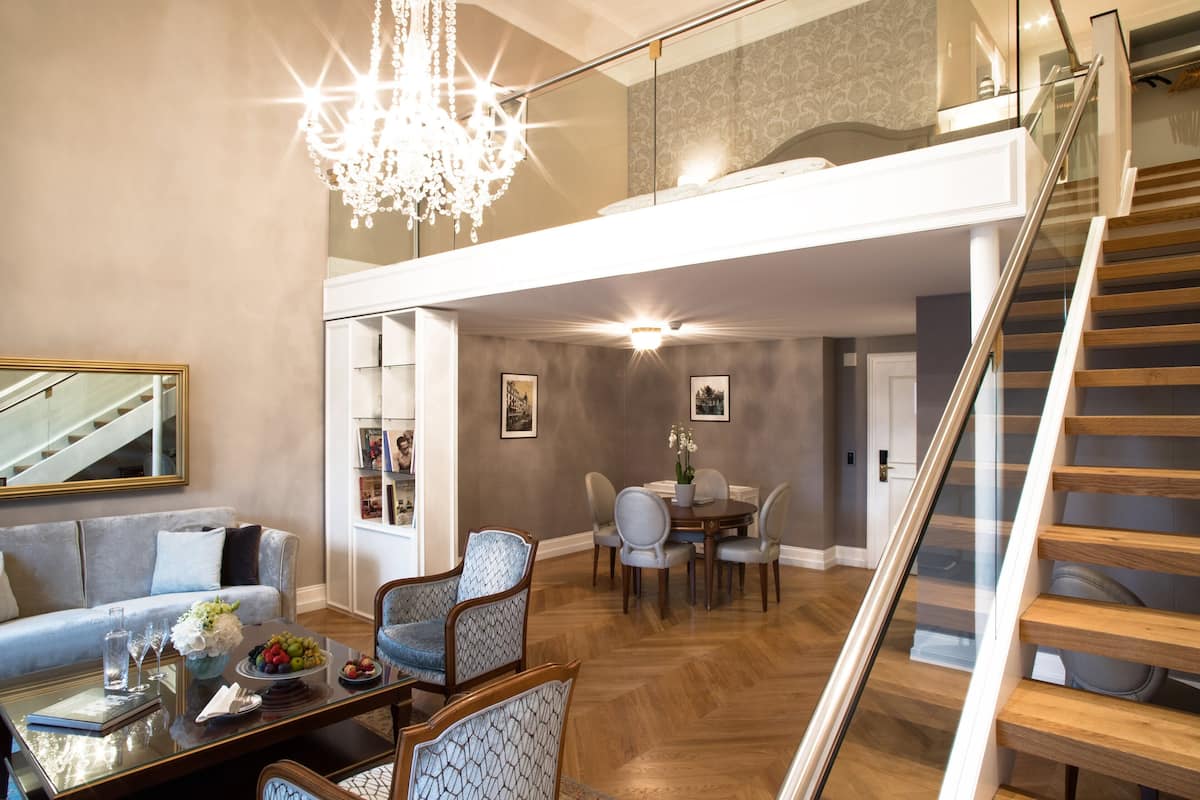 Un amplio salón con una mesa de comedor, sillas, un sofá y una escalera.