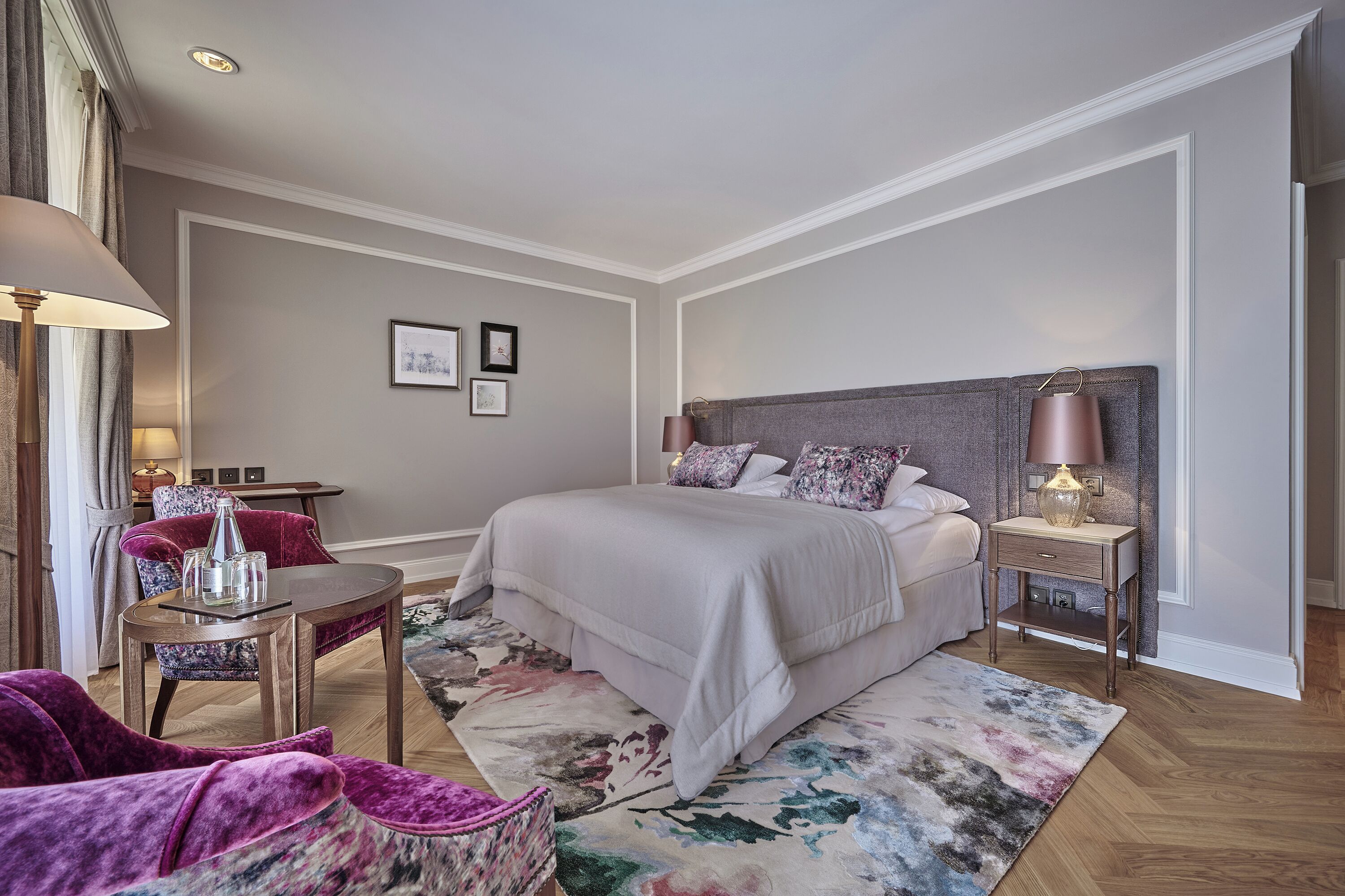 A bedroom with a bed, nightstand, lamp, chair, and a small table.