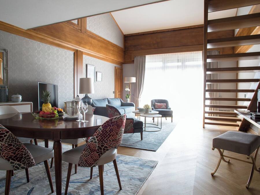 A modern living room with a dining area, a staircase, and a view of the outdoors.