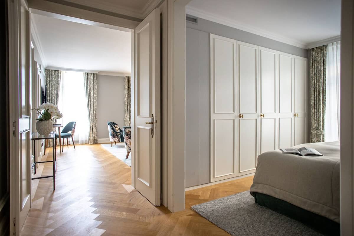 Un dormitorio con una cama grande, un armario, un escritorio con silla, y vista a un comedor.