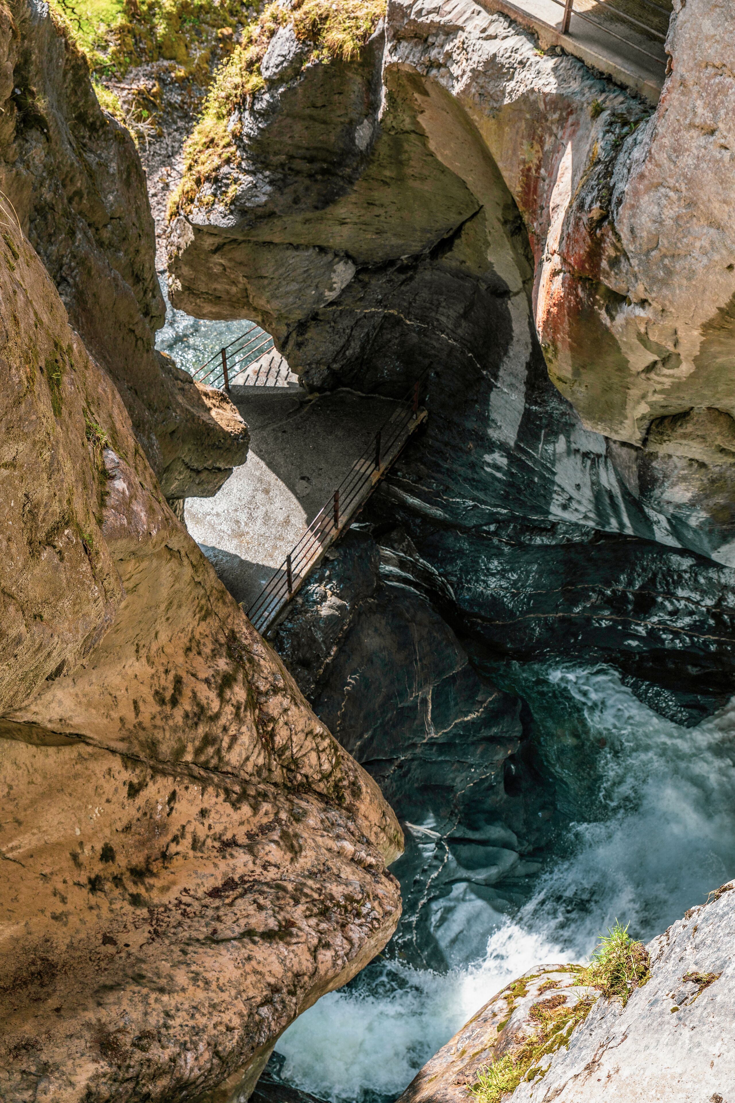 A rocky gorge with a bridge over a flowing river.