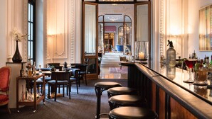 Eine Bar mit Hockern, einer Theke und Blick in einen Essbereich mit Tischen und Stühlen.