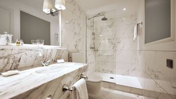 A modern bathroom with a marble vanity, a glass-enclosed shower, and a separate toilet.