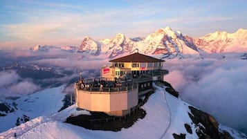 Ein mit Schnee bedeckter Berggipfel mit Aussichtsplattform und einem Gebäude mit rotem Schild.