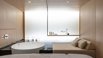 Un baño moderno con bañera, tocador y ventana con vistas al mar.