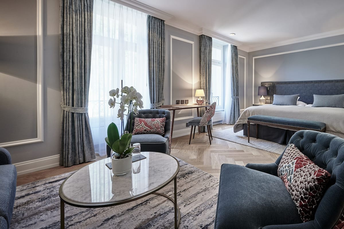 Una habitación de hotel moderna con una cama, dos sillones, una mesita y un escritorio.