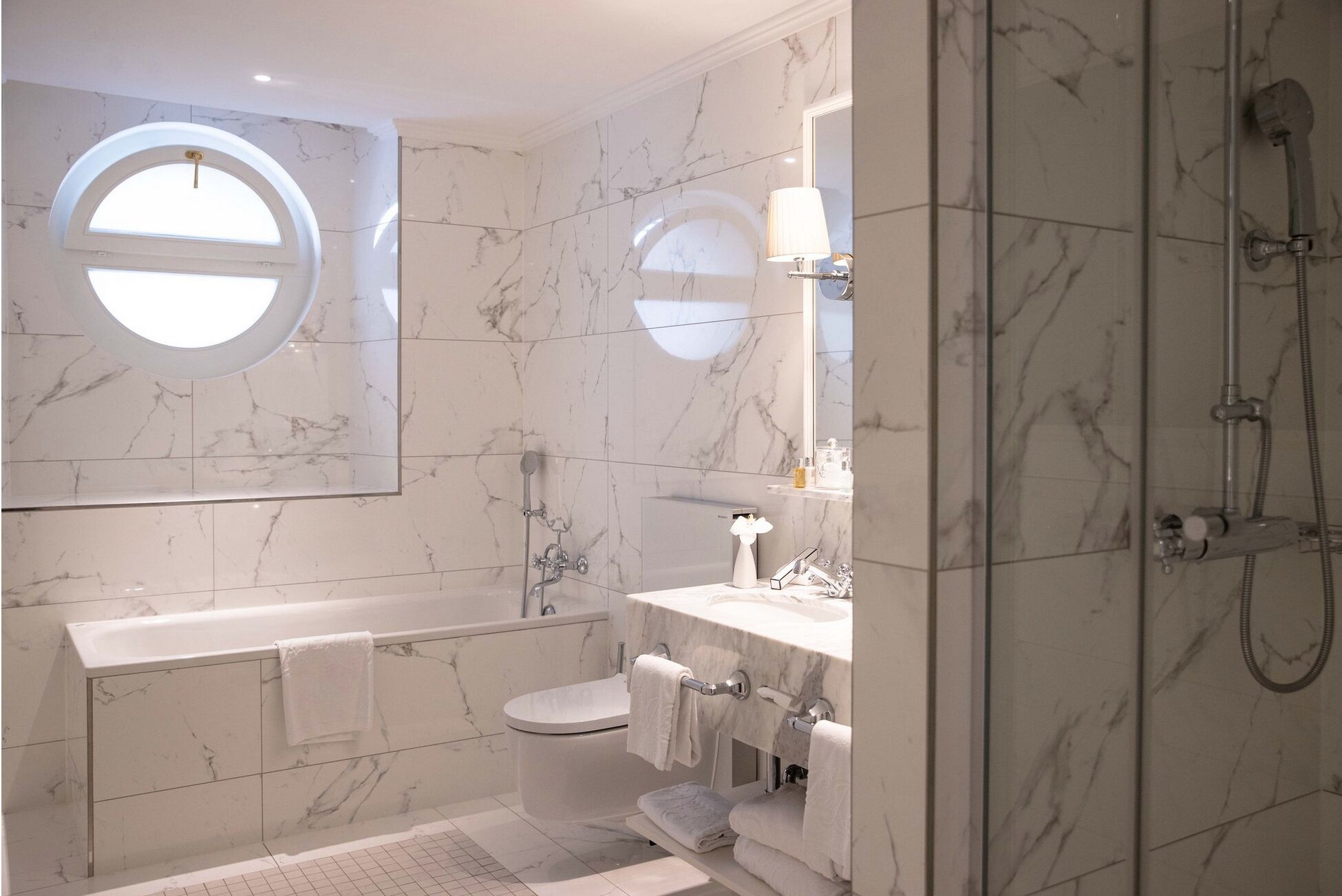 A modern bathroom with a bathtub, toilet, and shower.