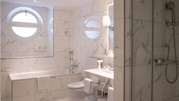A modern bathroom with a bathtub, toilet, and shower.
