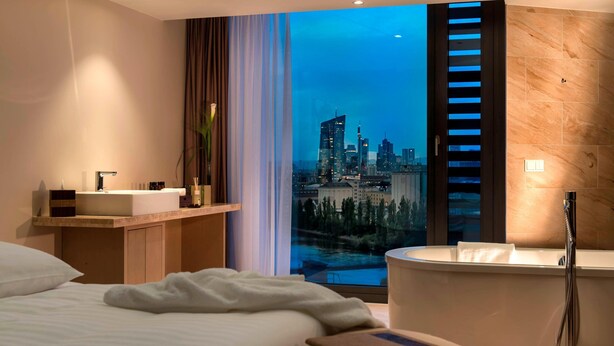 A modern hotel room with a city view, a bathtub, and a vanity with a sink. - Delta Hotels by Marriott Frankfurt Offenbach (Offenbach am Main)