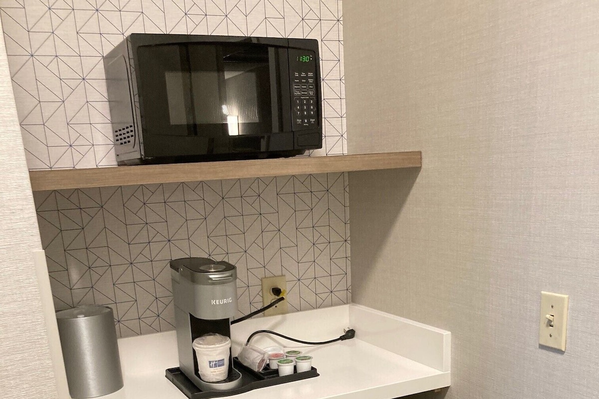 A compact kitchenette with a microwave, coffee maker, and dishwasher.