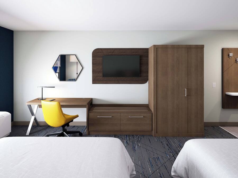 Habitación de hotel con dos camas, un escritorio con silla, un televisor fijado a un panel de madera y un armario.