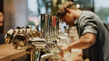 A bar with a row of taps and a person preparing drinks.