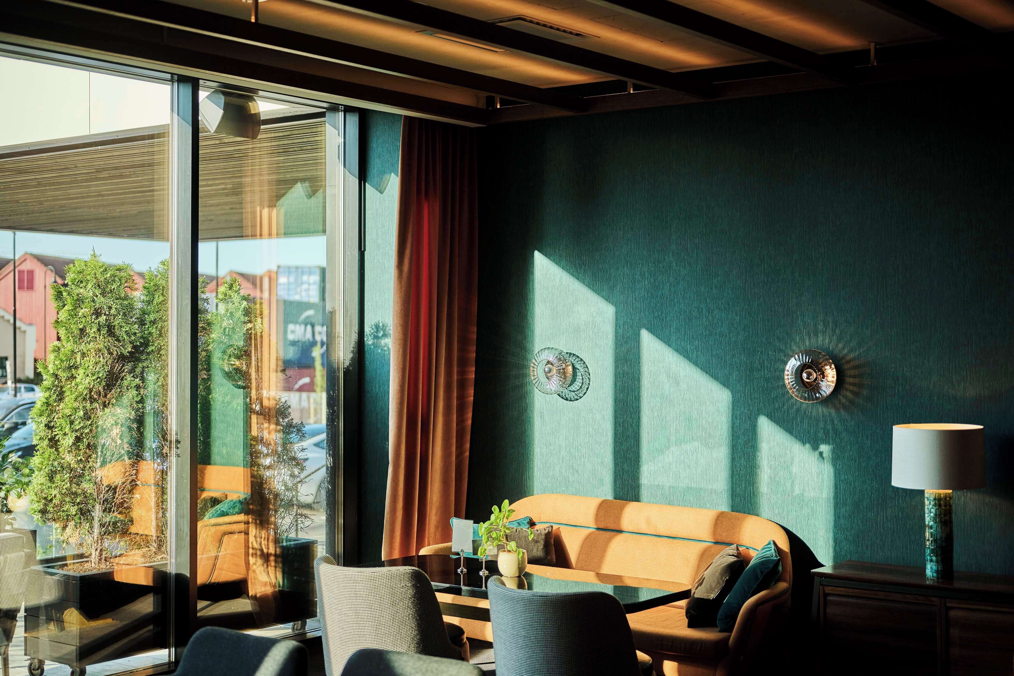Een moderne kamer met een glazen scheidingswand, een bank, een tafel met een plant en een lamp.