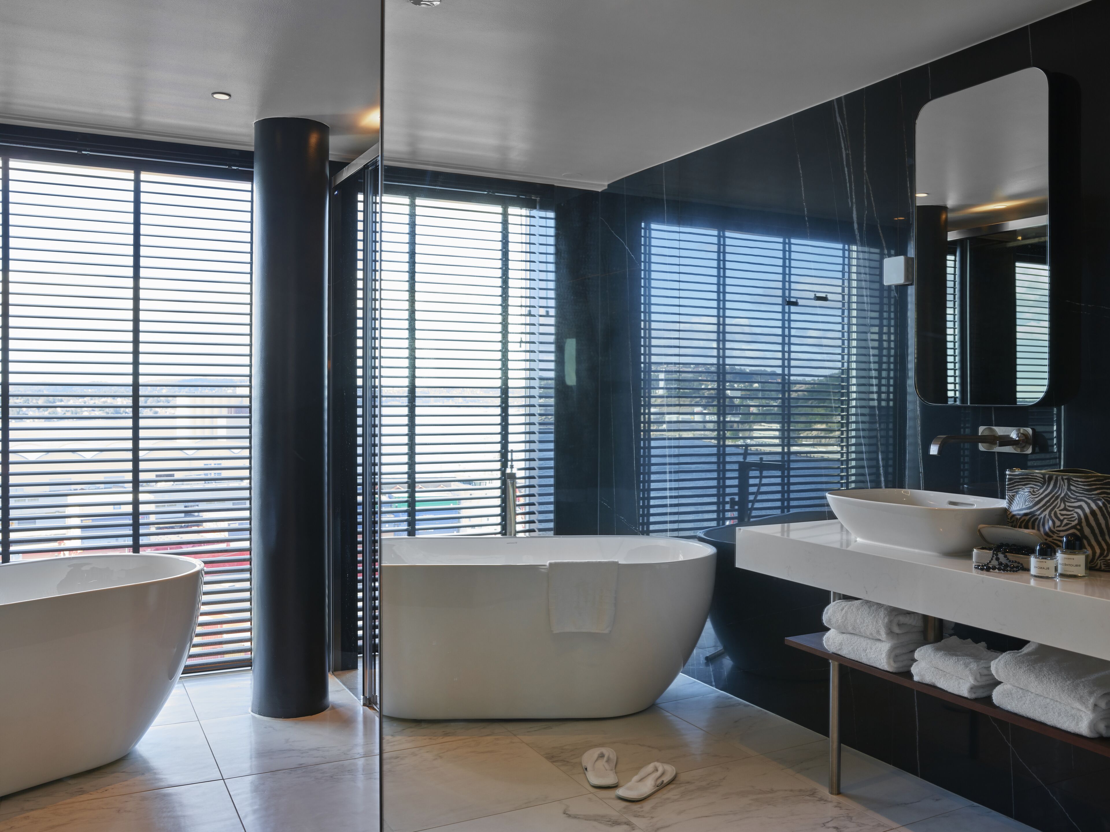 A modern bathroom with a freestanding bathtub, a large mirror, and a vanity with a sink.