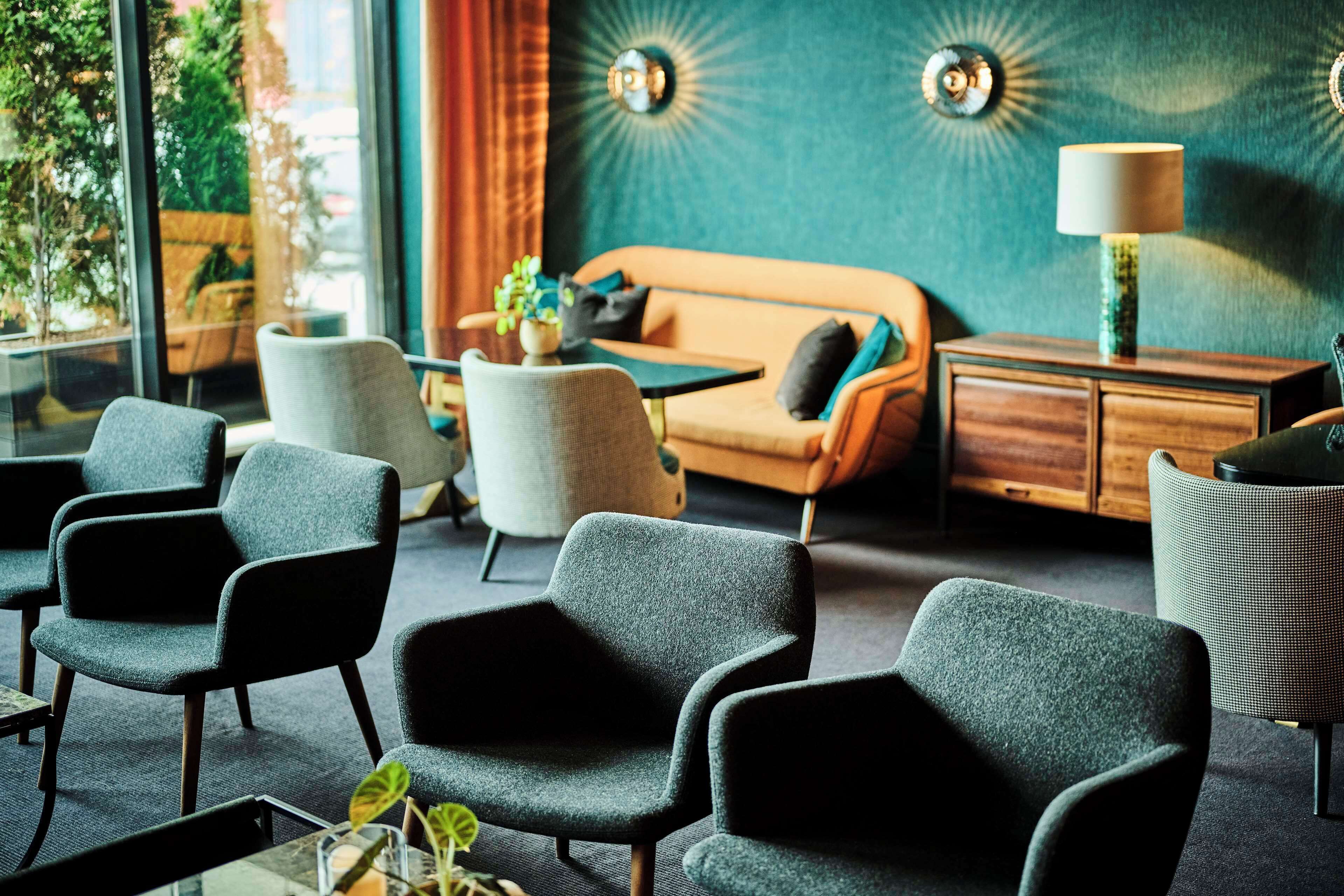 A modern lounge area with a sofa, armchairs, a coffee table, and a lamp.
