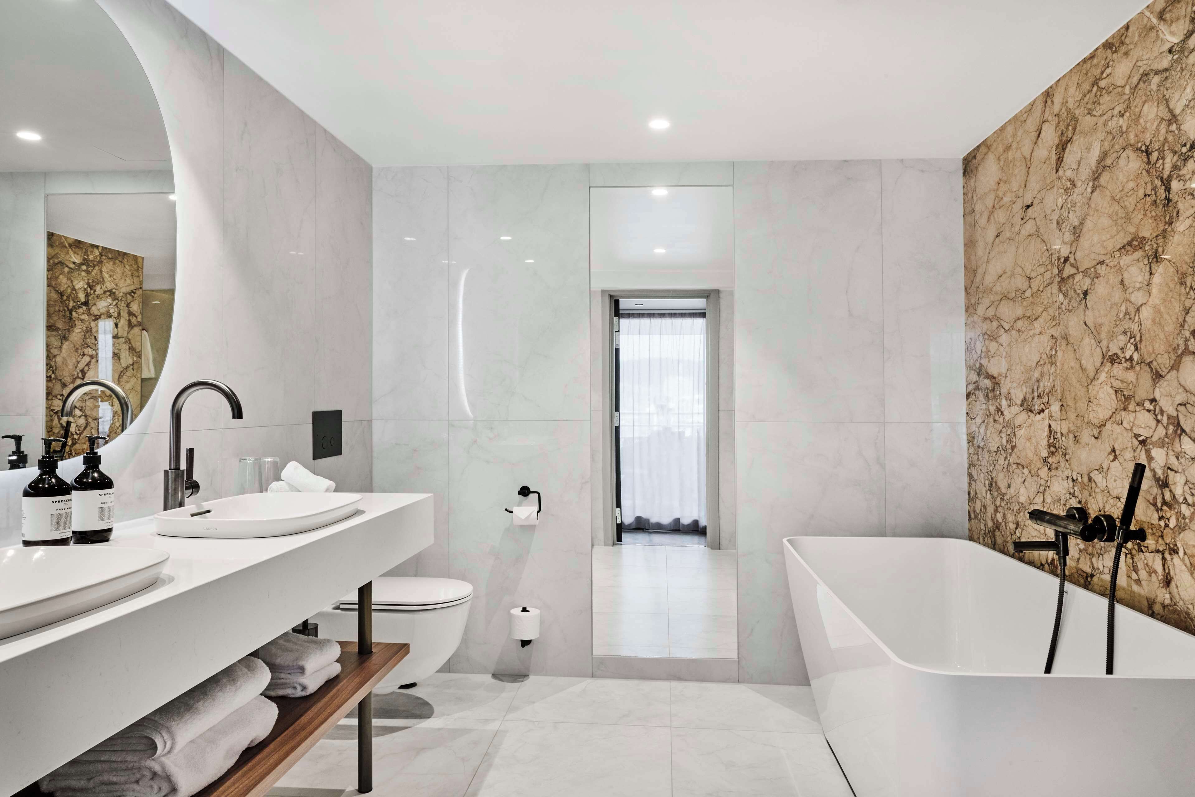 A modern bathroom with a white vanity, a bathtub, and a toilet.