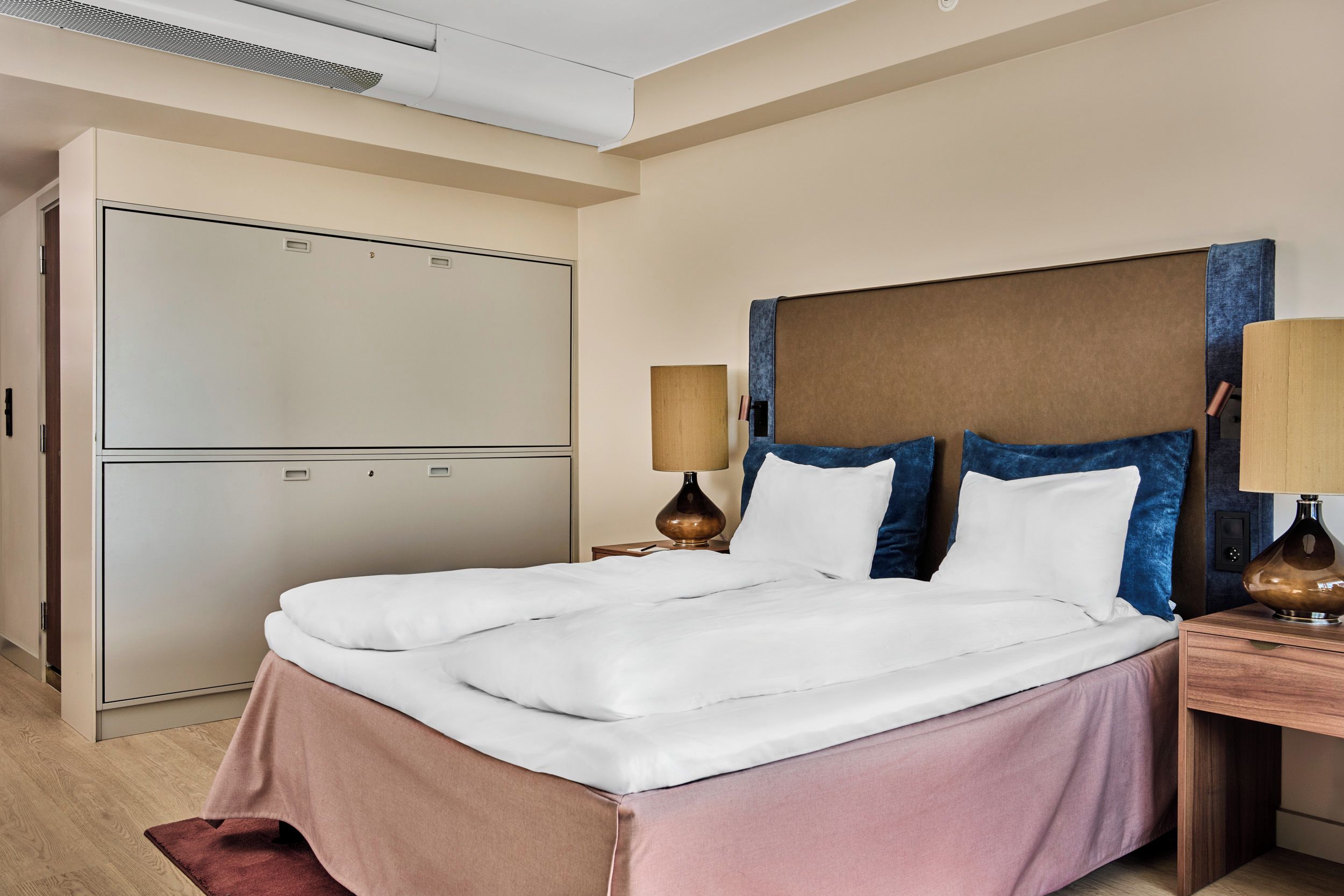 Ein Hotelzimmer mit einem großen Bett, einem Kleiderschrank und zwei Nachttischlampen.