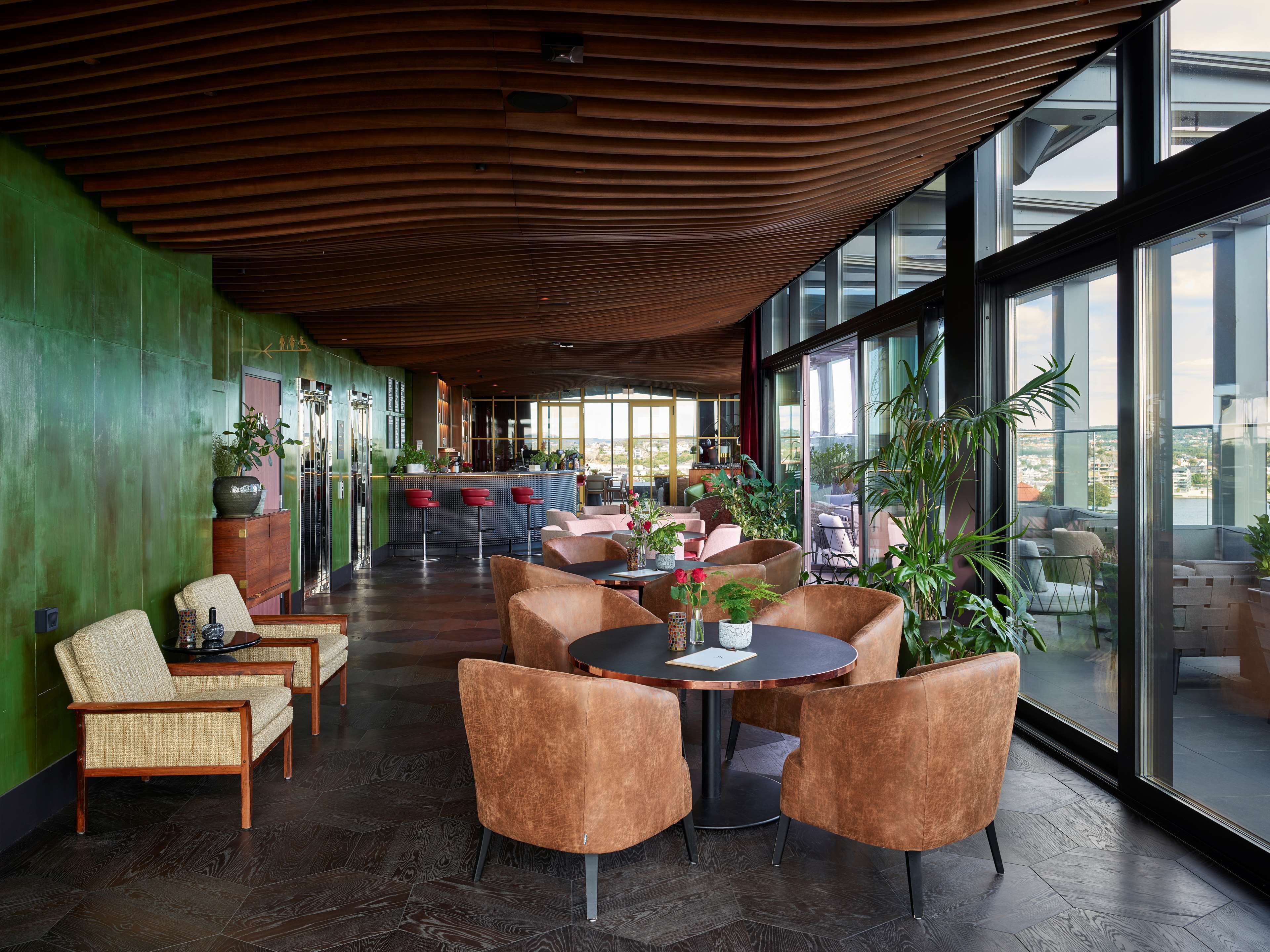 A modern interior with a bar area, seating, and large windows offering views.
