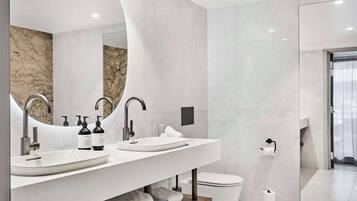 Un baño moderno con dos lavamanos, un espejo grande y un inodoro.