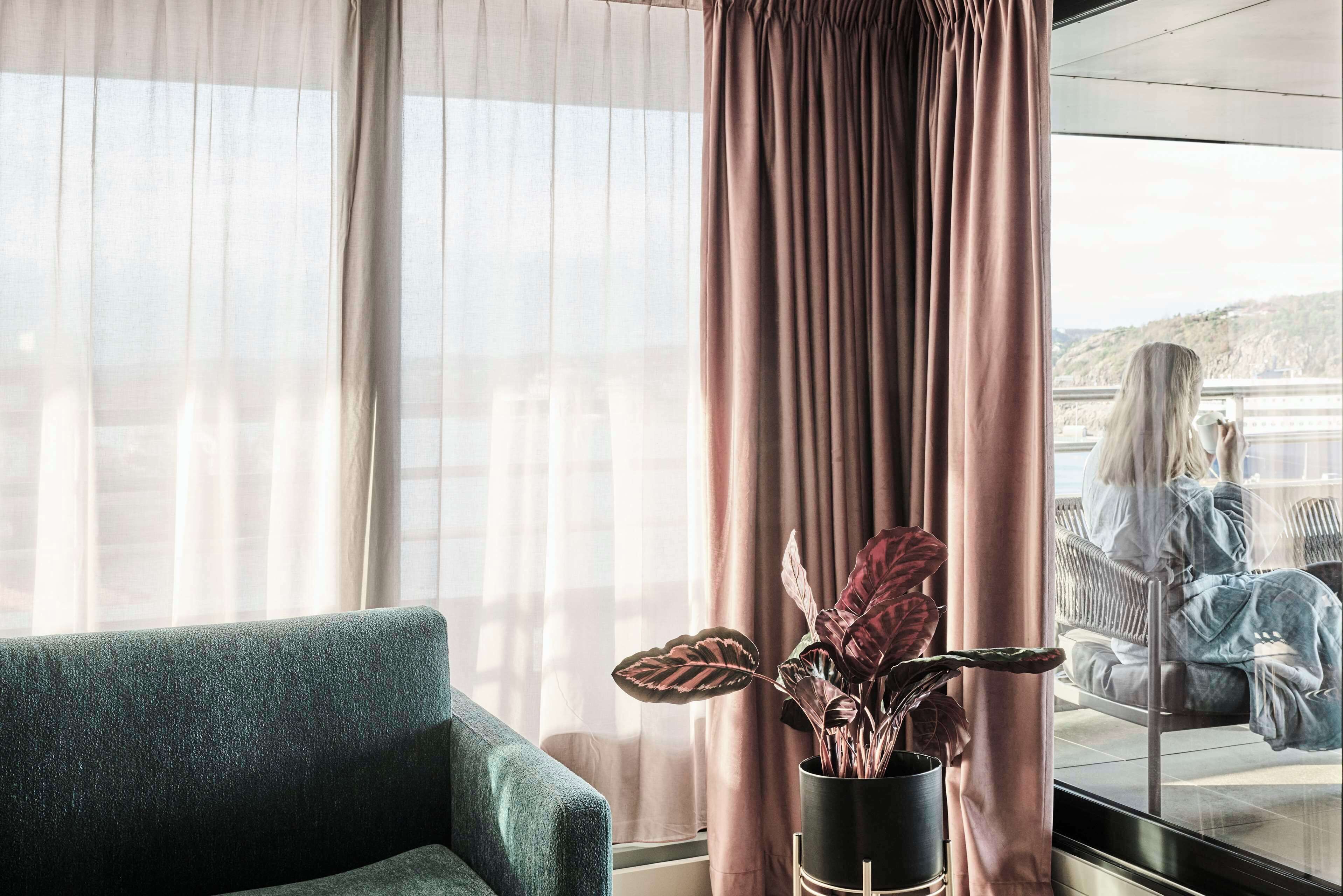 A room with a view of a balcony, a sofa, and a potted plant.