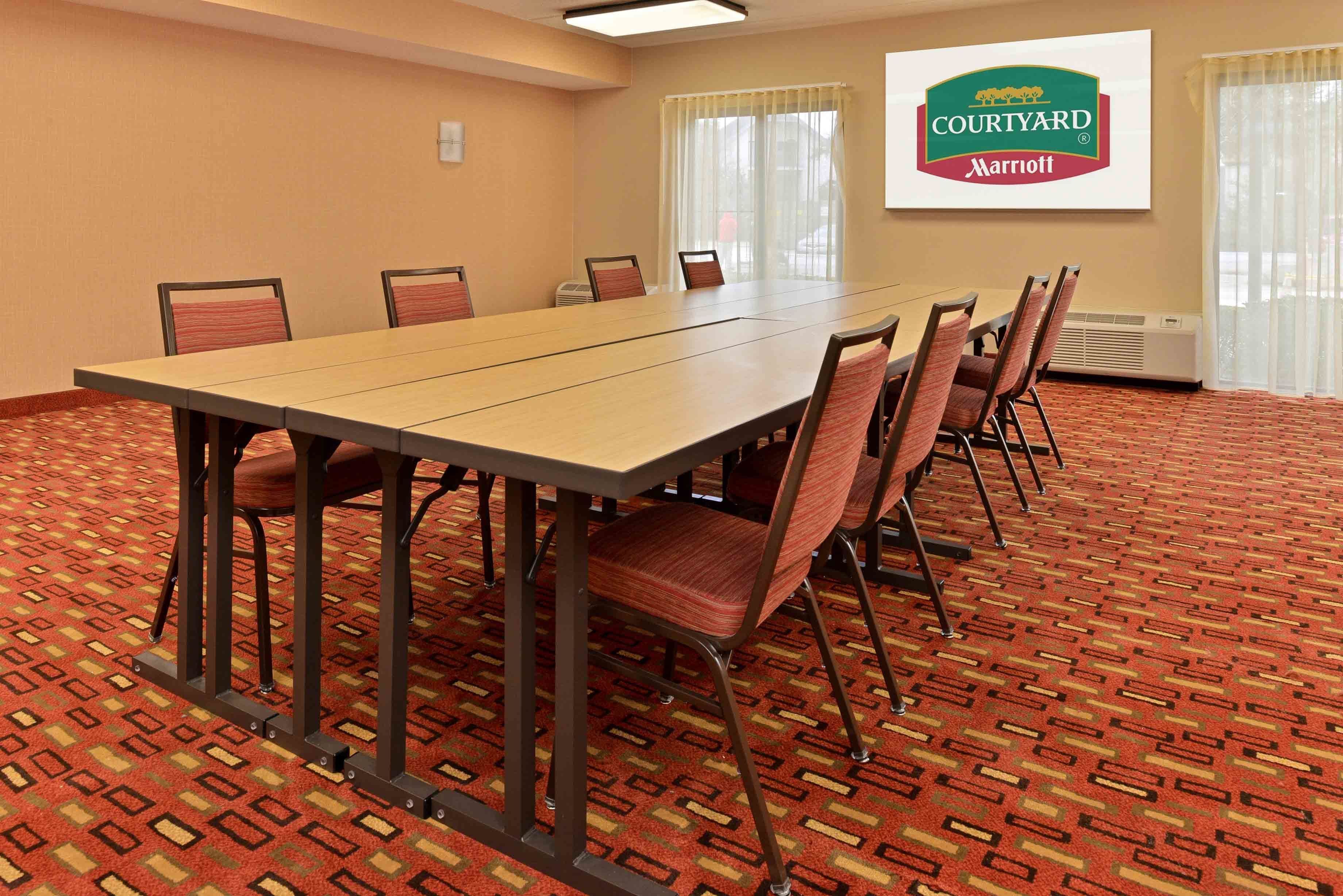 A conference room with a long table, chairs, and a large screen displaying the Courtyard Marriott logo.