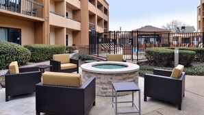An outdoor patio area with wicker furniture and a stone fire pit. - Courtyard by Marriott Dallas Northwest (Dallas)