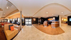 A spacious lobby with a reception desk, seating area, and a large screen. - Courtyard by Marriott Dallas Northwest (Dallas)